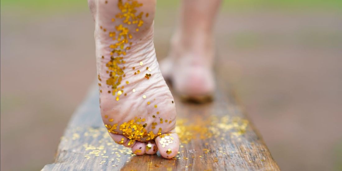 Gepflegter Fuß mit goldenem Glitzer auf einem Holzbalken – medizinische Fußpflege in Marsberg